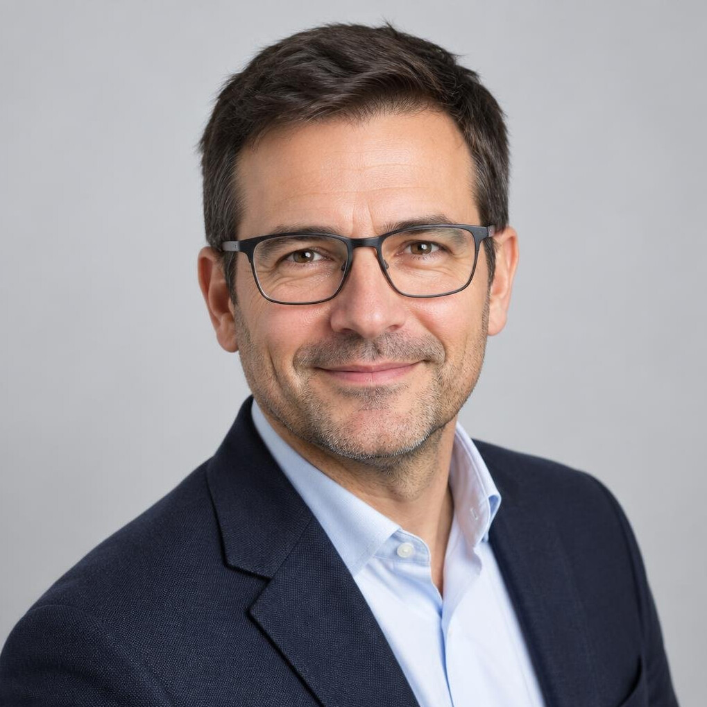Studio portrait of a European man with short dark hair and glasses